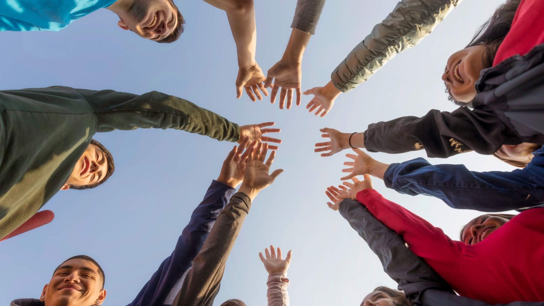 Peoples hands going to the centre of a group in a circle symbolizing community